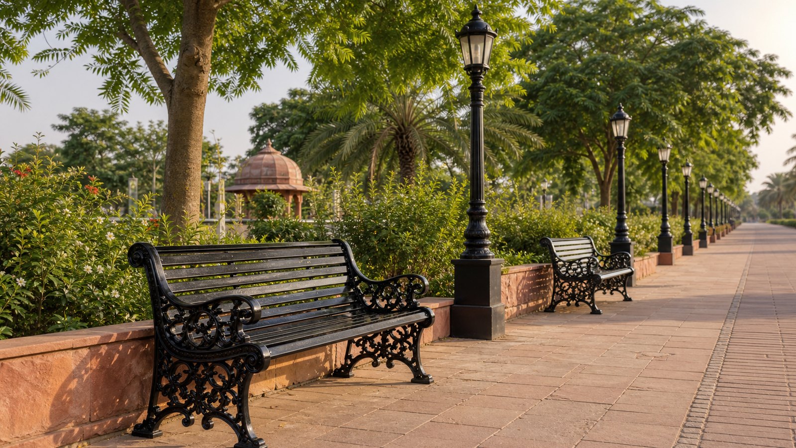 Black cast iron benches and heritage lamp posts installed along an Indian civic park promenade